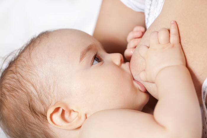 Baby liegt an der Brust und wird gestillt.
